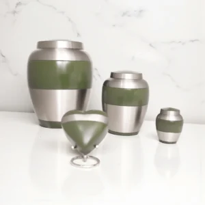 Sage green and silver two-tone brass keepsake urn, displayed on a white marble countertop, modern memorial.