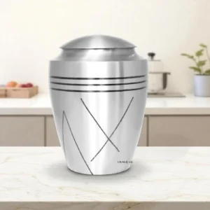 Brushed brass cremation urn on a marble surface, top-down view showing lid and polished finish.