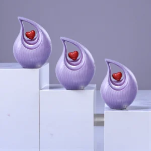 Three Purple Timeless Heart Cremation Urns with red heart accents displayed on marble slabs in a staircase setup