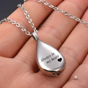"Always in my heart" teardrop urn necklace for ashes, shown held gently in the palm of a hand to show its personal size.
