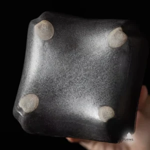 The bottom view of the 'Gilded Earth' ceramic pet urn, showing the dark, unglazed base and the four small, raised feet.