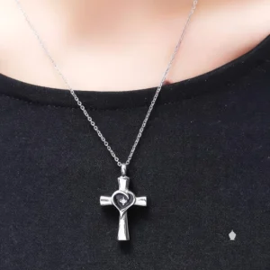 Stainless steel Heart Cross Urn Necklace shown worn by a person, hanging on a silver chain against a black shirt.