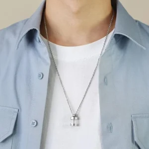 A man wearing a stainless steel urn necklace with a clear vial pendant, shown hanging naturally over a white t-shirt and blue shirt.