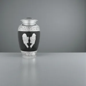 Black and silver 'Midnight Wings' adult cremation urn with angel wings, elegantly displayed on a grey marble surface with a subtle reflection.