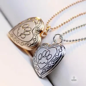 The gold and silver variations of the paw print heart photo locket, shown side-by-side.