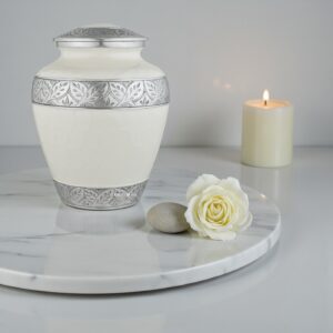 Silver Lining White Adult Cremation Urn on a marble slab with a lit candle and a fresh white rose.