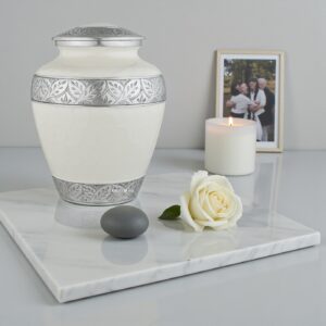 Silver Lining White Adult Cremation Urn on marble with candle, white rose, and a blurred family photo.
