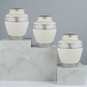 Three Silver Lining White Adult Cremation Urns arranged in a descending stair-like formation on a marble slab.