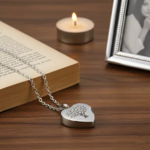 HDR enhanced Tree of Life heart urn necklace resting on a wooden table next to an open book and a cherished photo frame, creating a warm memorial scene.