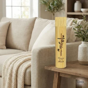 Biodegradable bamboo scattering urn with engraved Cross, Rose, and Dove design displayed on a wooden side table next to a beige sofa in a peaceful living room