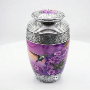 High angle view of the Sunrise Serenade adult cremation urn, showcasing the intricately engraved silver lid with its matching painted hummingbird inlay, along with the scenic purple body.