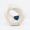 Modern white alabaster cremation urn shaped like an infinity loop with a polished sapphire blue heart in the center.