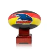 premium Adelaide Crows AFL Cremation Urn in the shape of a football with team colours and logo, mounted on a polished timber base against a clean white background.