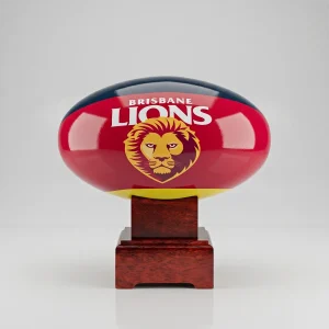 A front-on view of the Brisbane Lions AFL cremation urn showing the official club logo and maroon colours on a polished mango wood display stand.