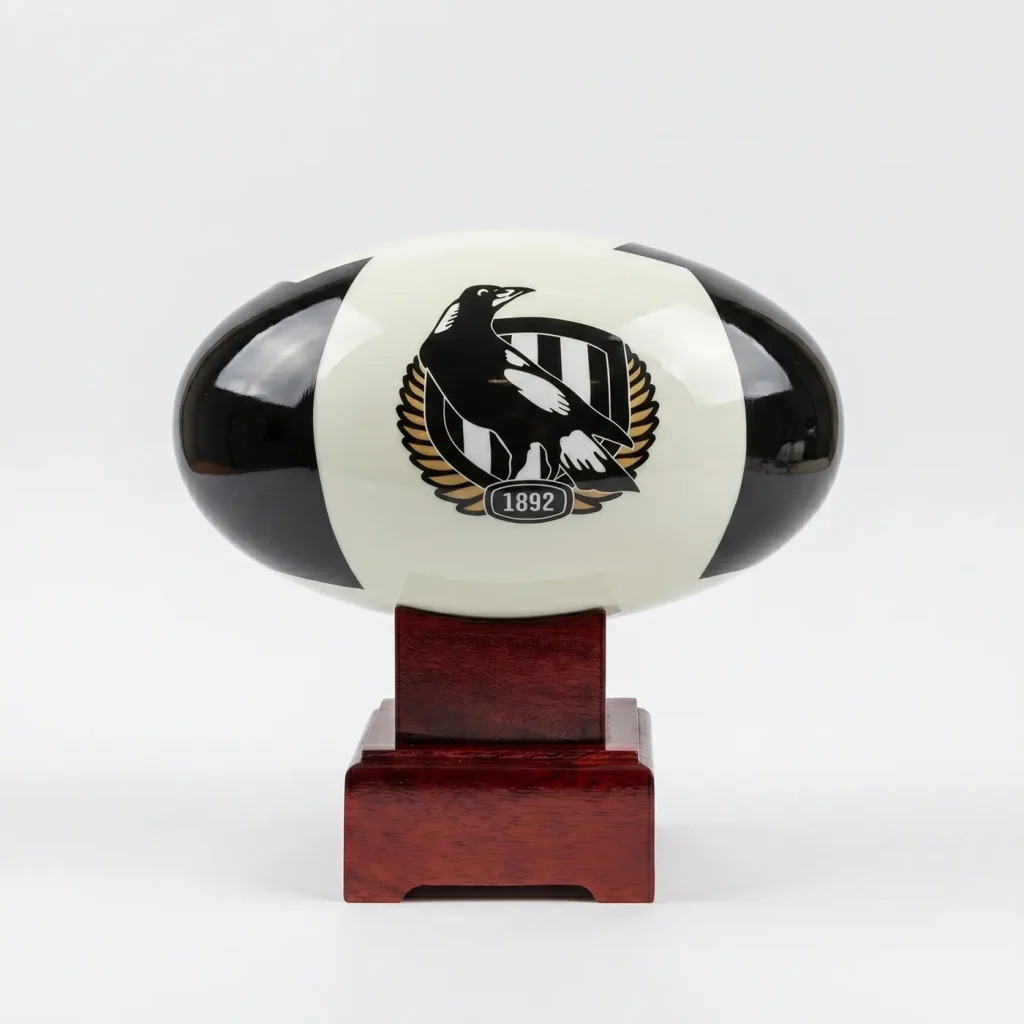 Front view of the Collingwood Magpies AFL Cremation Urn, featuring the classic black and white team emblem and resting on a polished solid timber base.