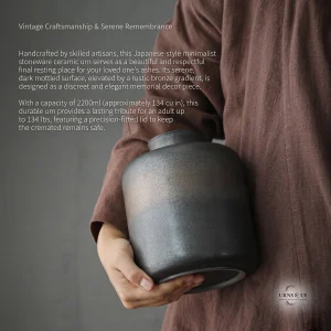 Person in linen robe holding a handcrafted Japanese-style stoneware ceramic cremation urn for ashes with a mottled grey and bronze glaze.