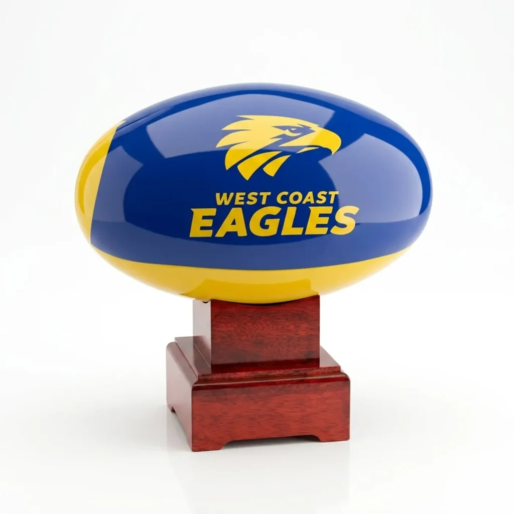 Front view of a West Coast Eagles AFL urn featuring a blue and gold aluminium football on a polished timber base.