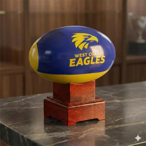 West Coast Eagles AFL memorial urn displayed elegantly on a stone slab in a home setting alongside sports memorabilia.