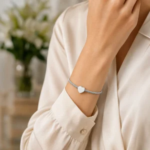 Lifestyle shot of a polished silver heart urn bracelet on a woman's wrist, styled in a bright Australian setting. High-quality cremation jewelry for ashes, offered at the most competitive price in Australia.