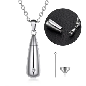 Silver teardrop cremation urn necklace pendant with a small crystal, shown with its screw-top open, alongside a miniature metal filling funnel and pin.