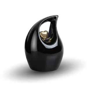 Black teardrop keepsake urn for ashes featuring a suspended small golden heart, isolated on a white background.